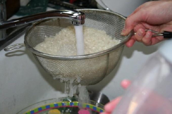 Operite rižu u cjedilo udoban s tekućom vodom.